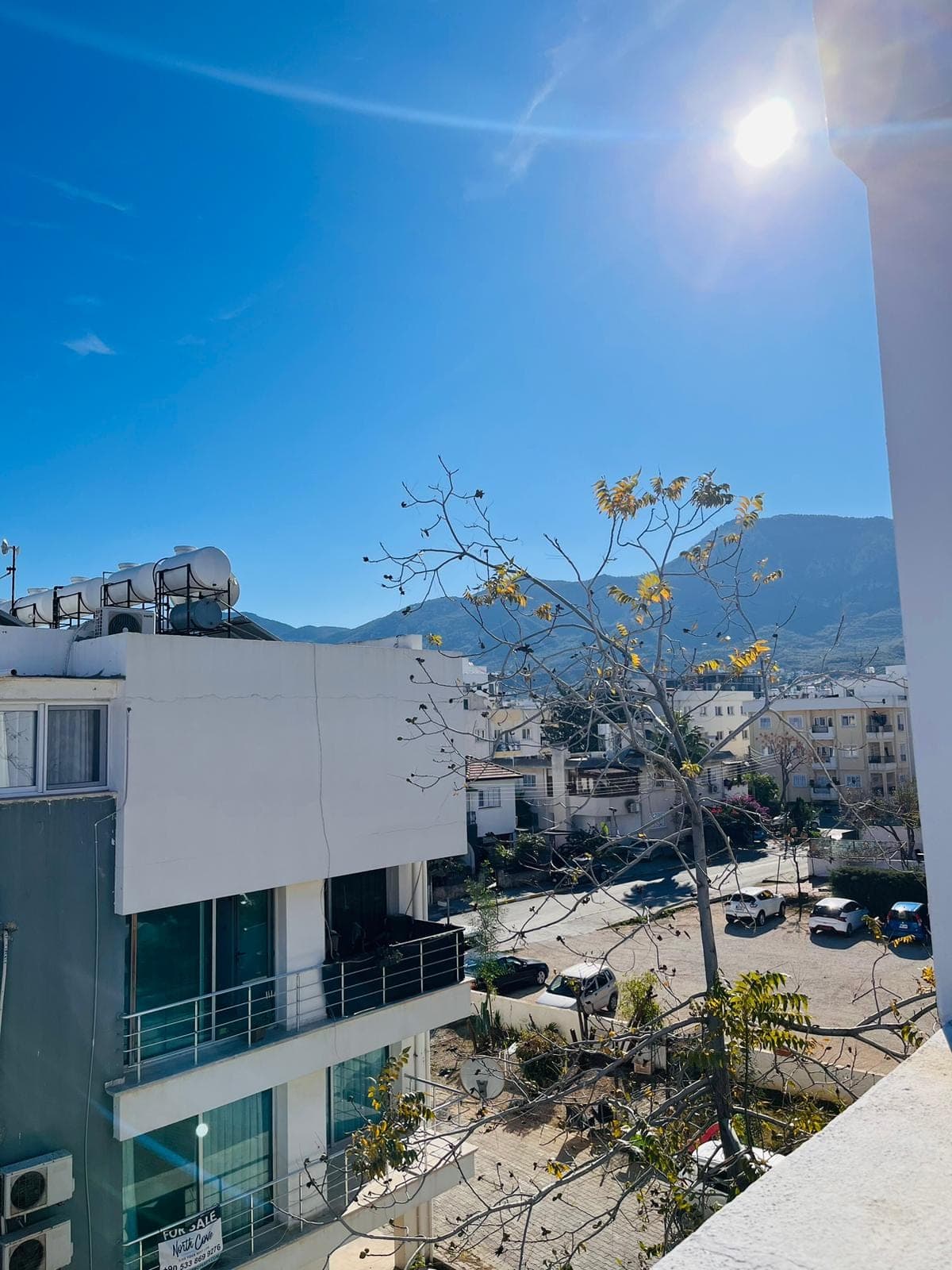 Spacious balcony with city and mountain views on a sunny day