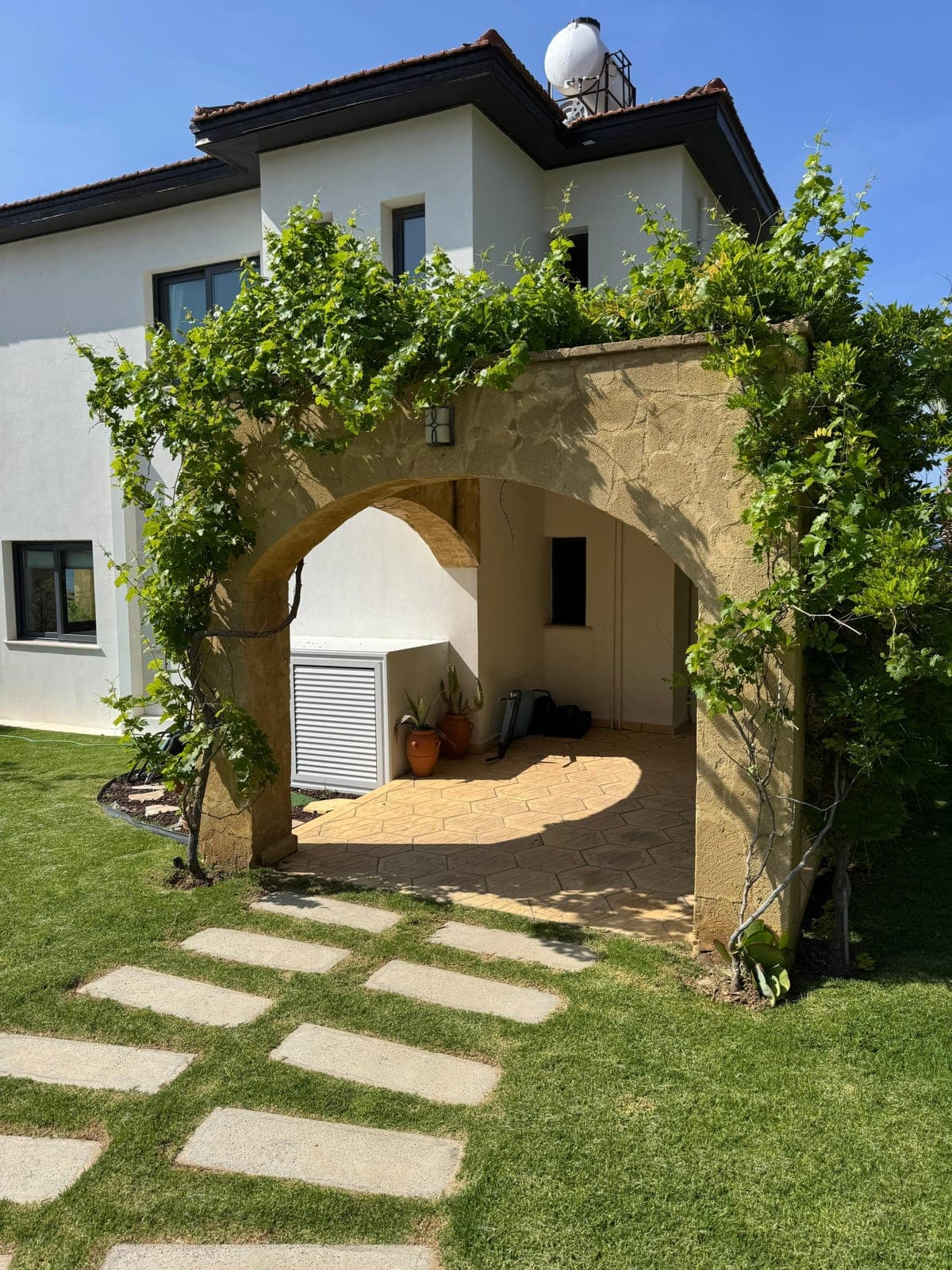 Arched entrance and exterior of the house within a green garden