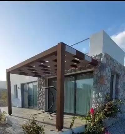 Taş detaylı müstakil evin pergolalı terası ve bahçesi