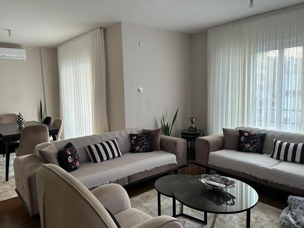 Spacious living room and dining area with light curtains and AC unit.