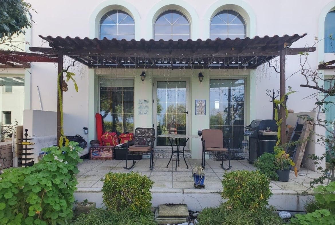 Exterior with arched windows and a pergola-covered seating area