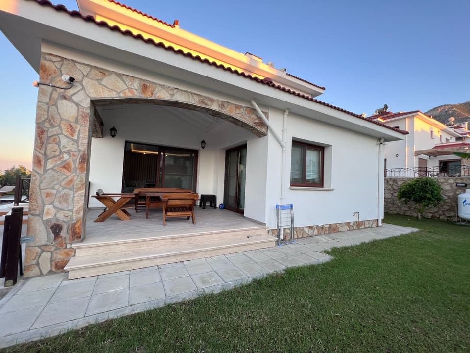 Taş detaylı, beyaz cepheli müstakil villa ve yeşil bahçe