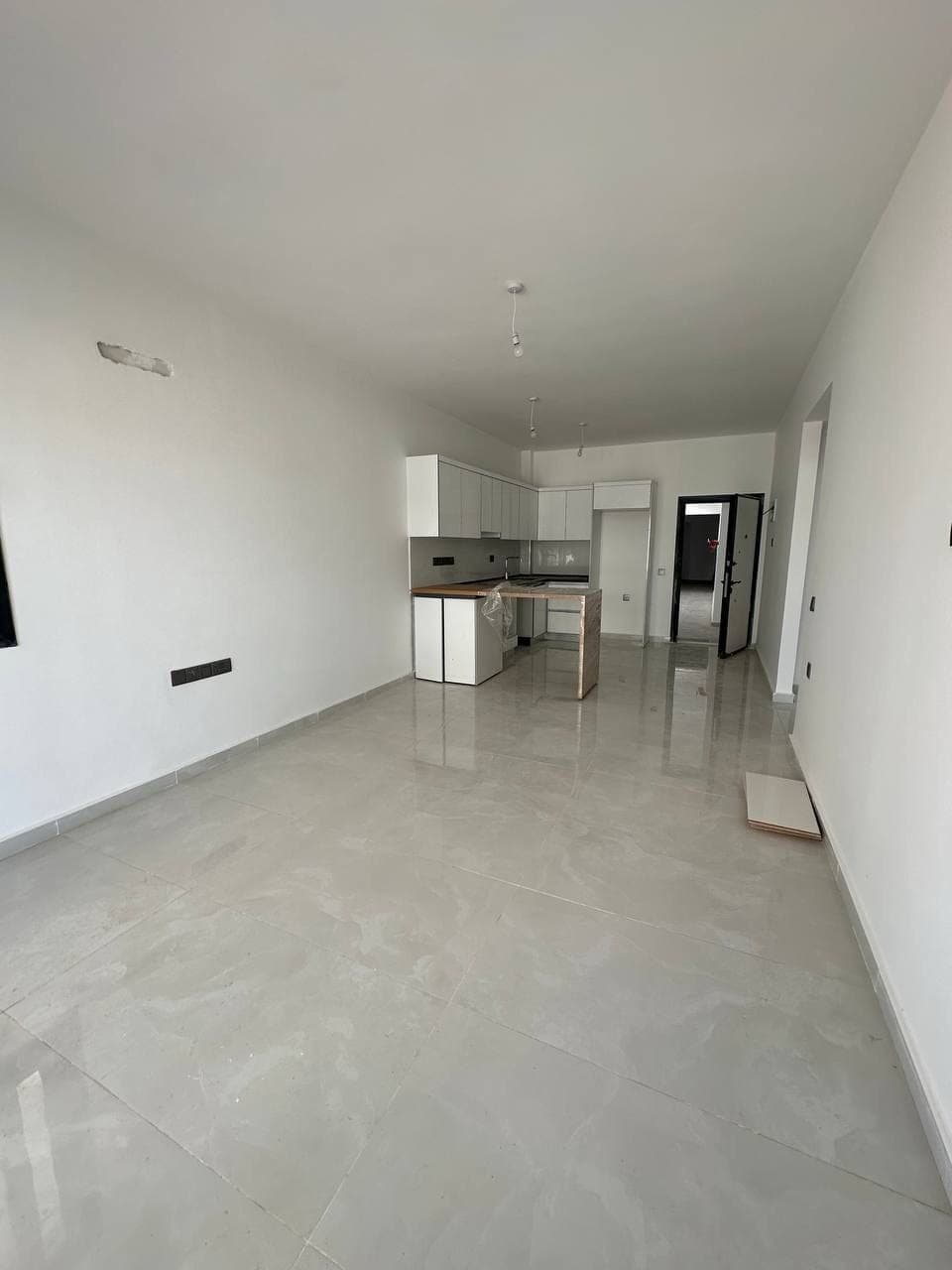 Open-plan living room and built-in kitchen area with tiled floor.