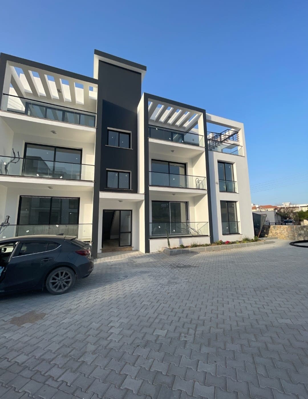 Modern designed building exterior with white and black details and parking area.