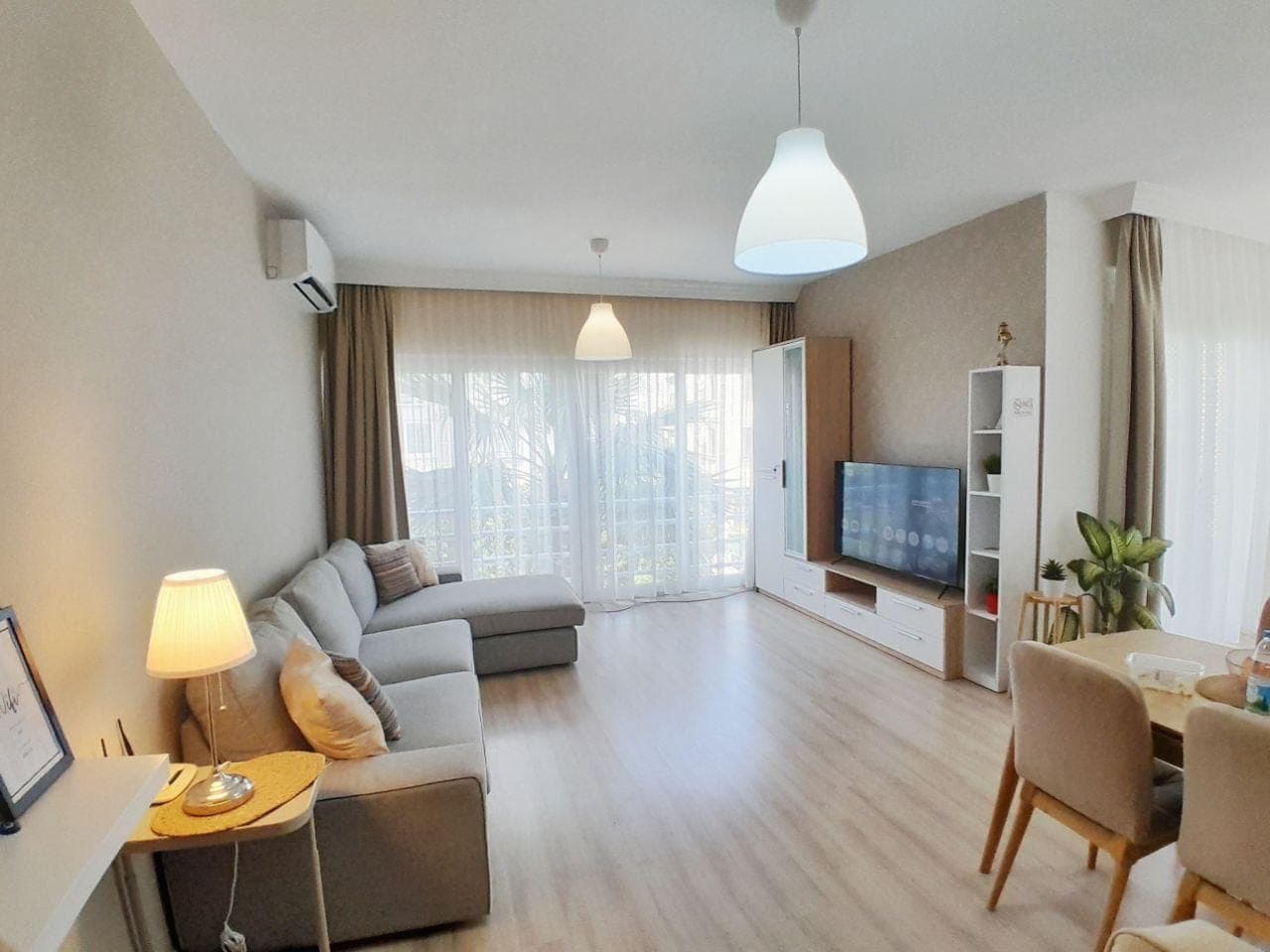 Spacious living room with L-shaped sofa, TV unit, and dining table.