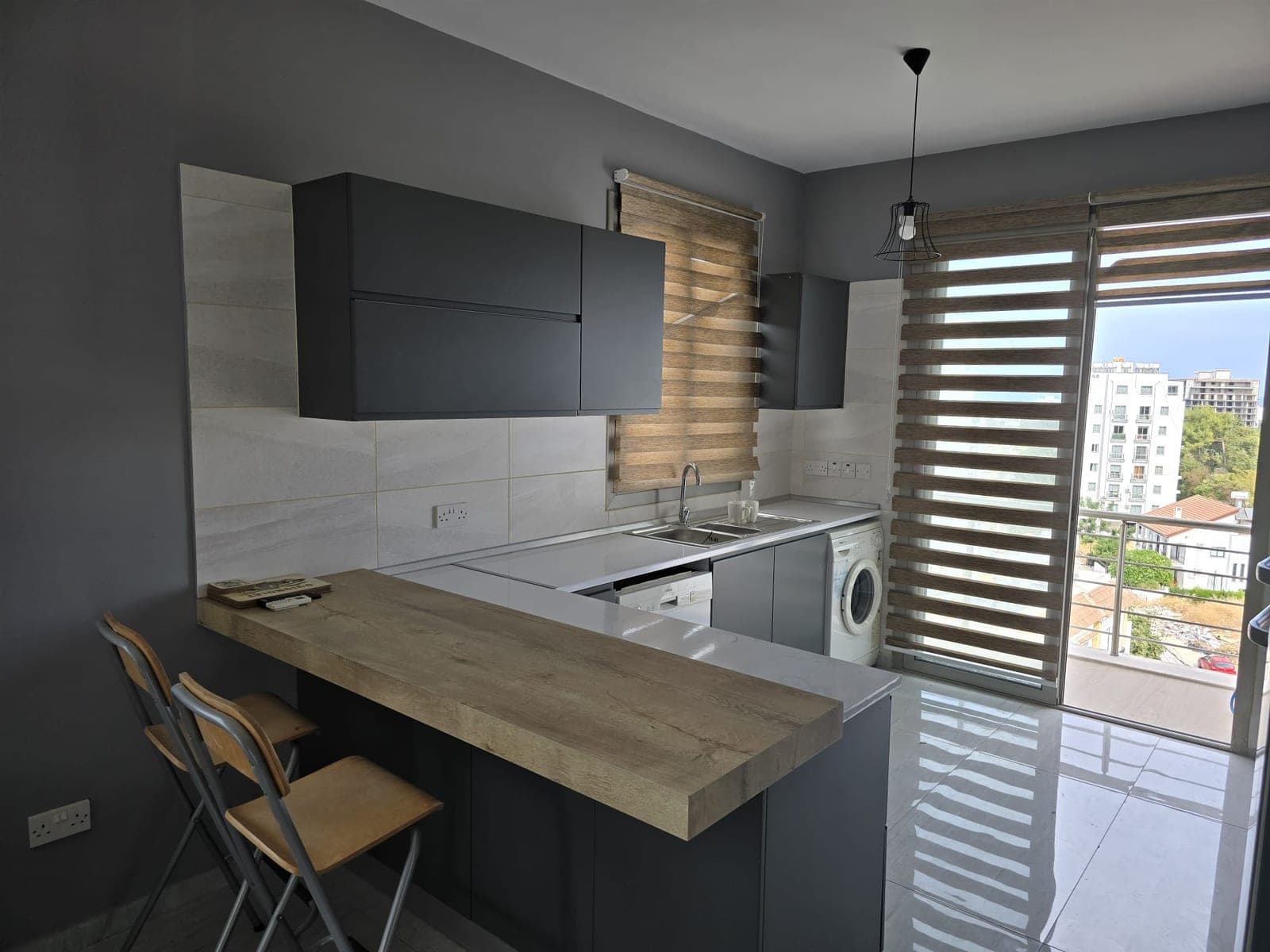 Modern kitchen with bar counter and balcony view.