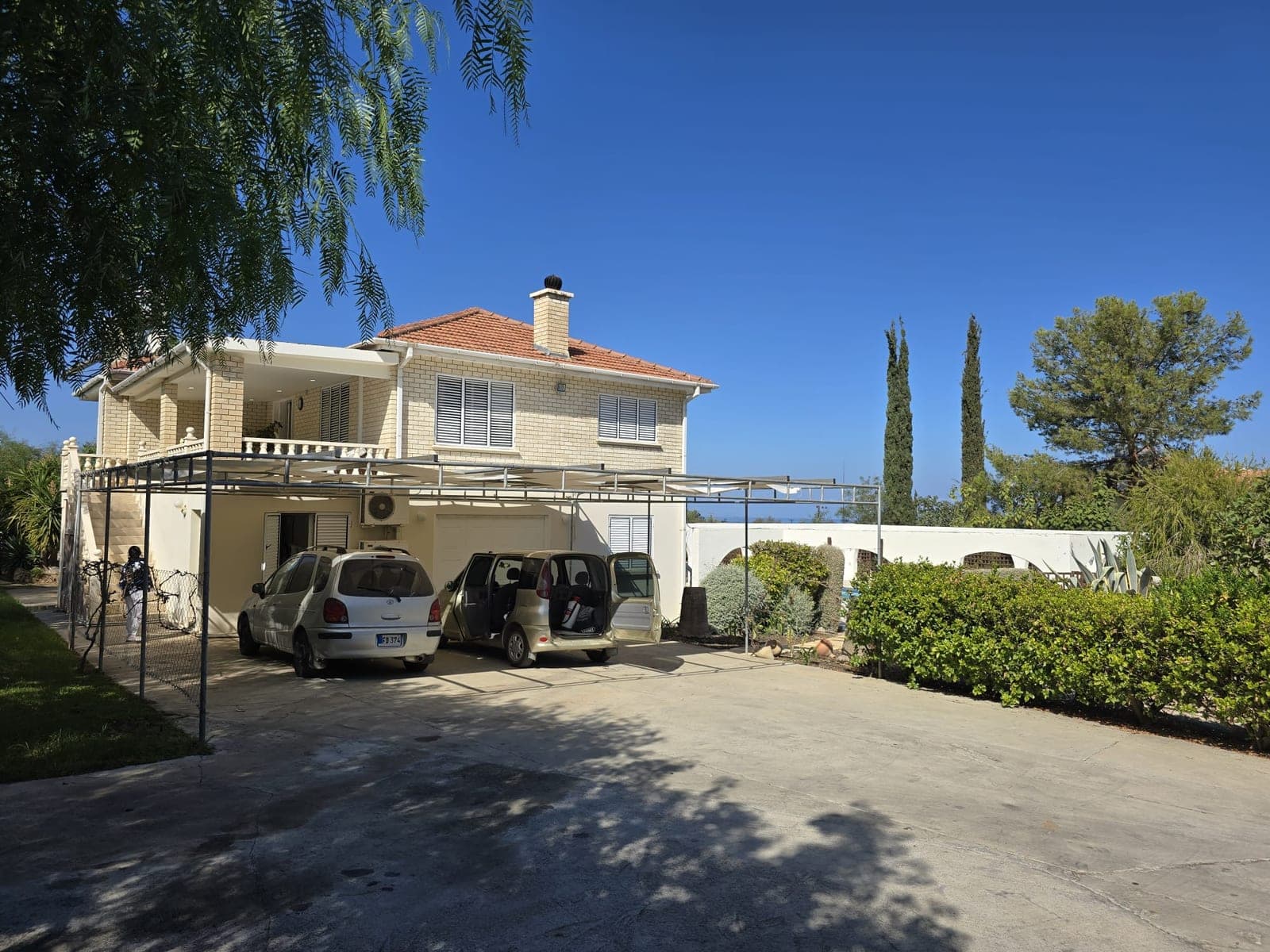 Exterior of a detached villa with spacious parking and green garden