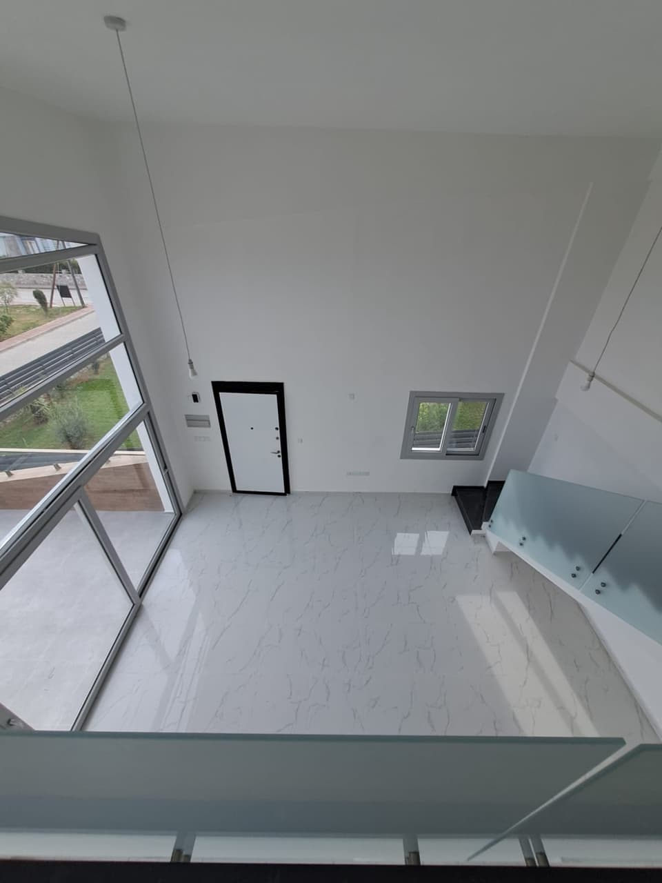 Geniş pencereli, yüksek tavanlı boş salon ve dış mekan manzarası