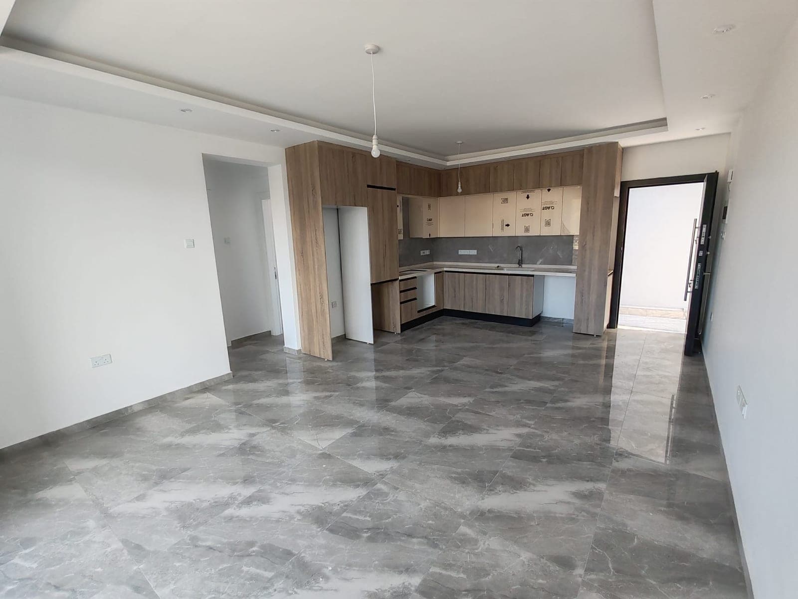 Open-plan living room and built-in kitchen area, gray marble floor.
