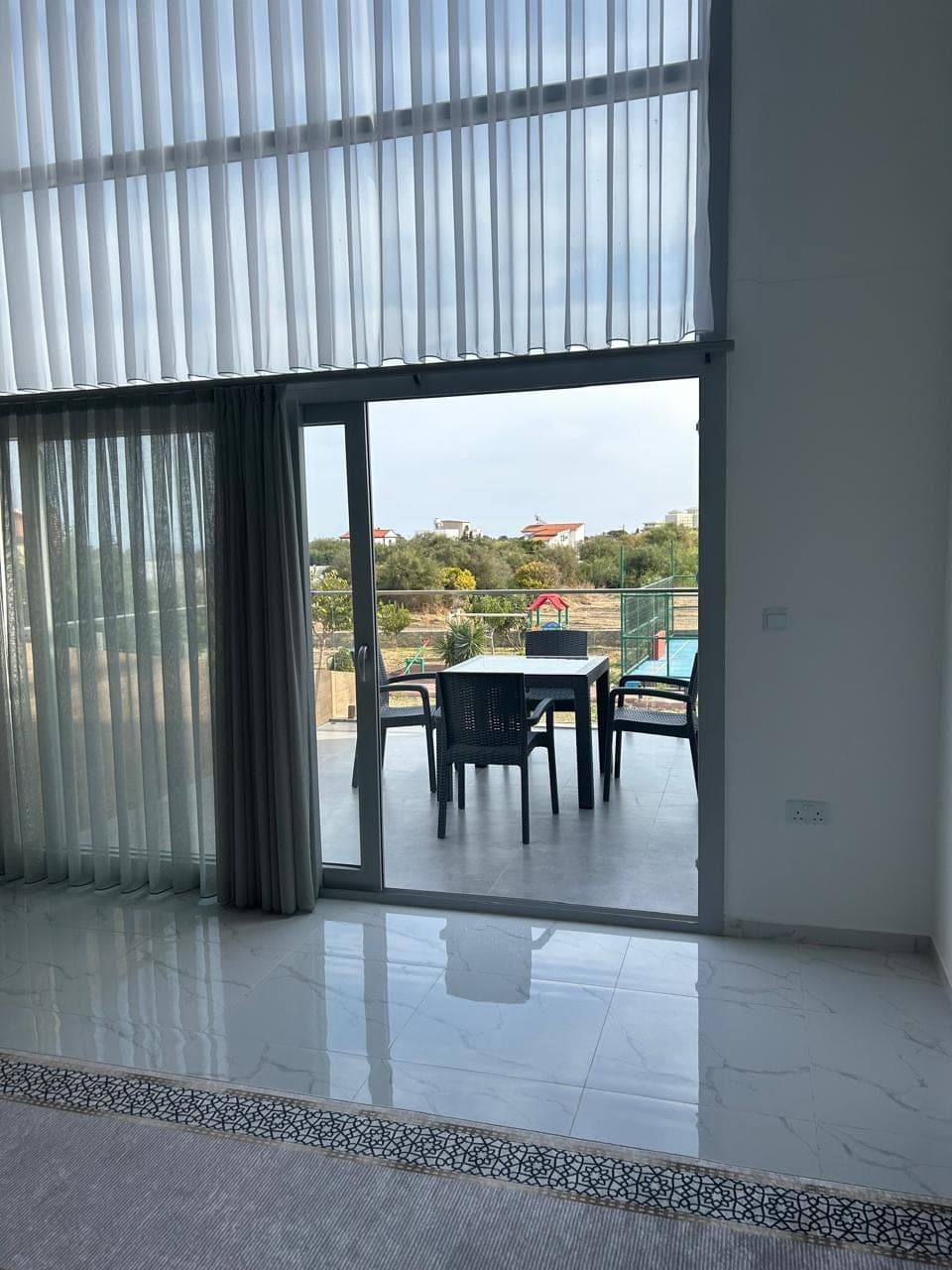 Outdoor view with pool and playground visible through wide glass door