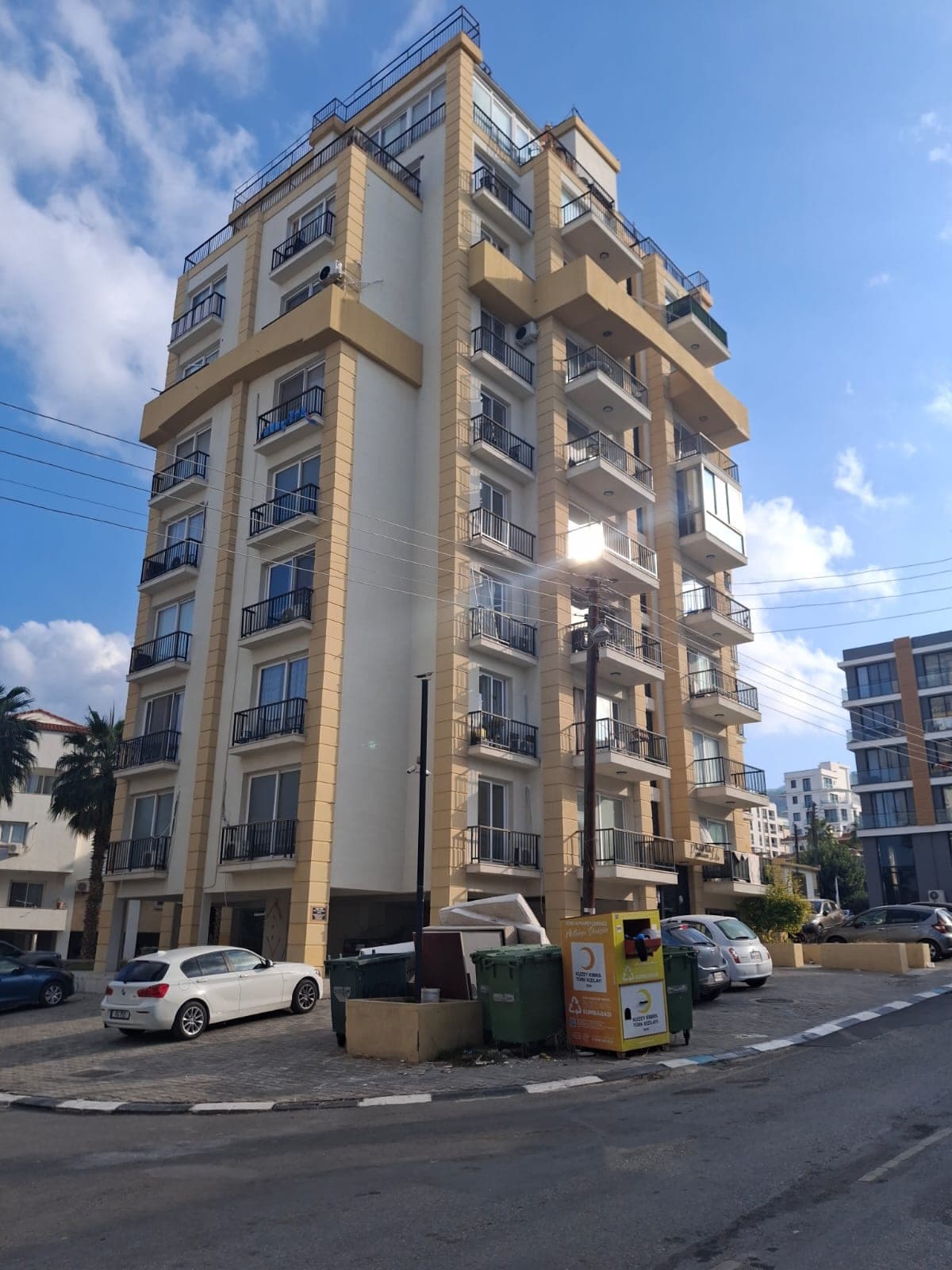 Exterior of a multi-story apartment building with parking area in front.