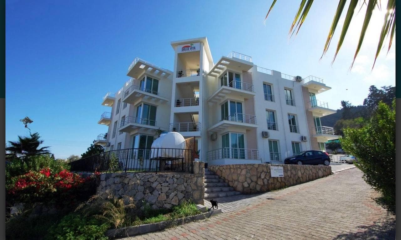 Exterior of a modern apartment building with parking area.