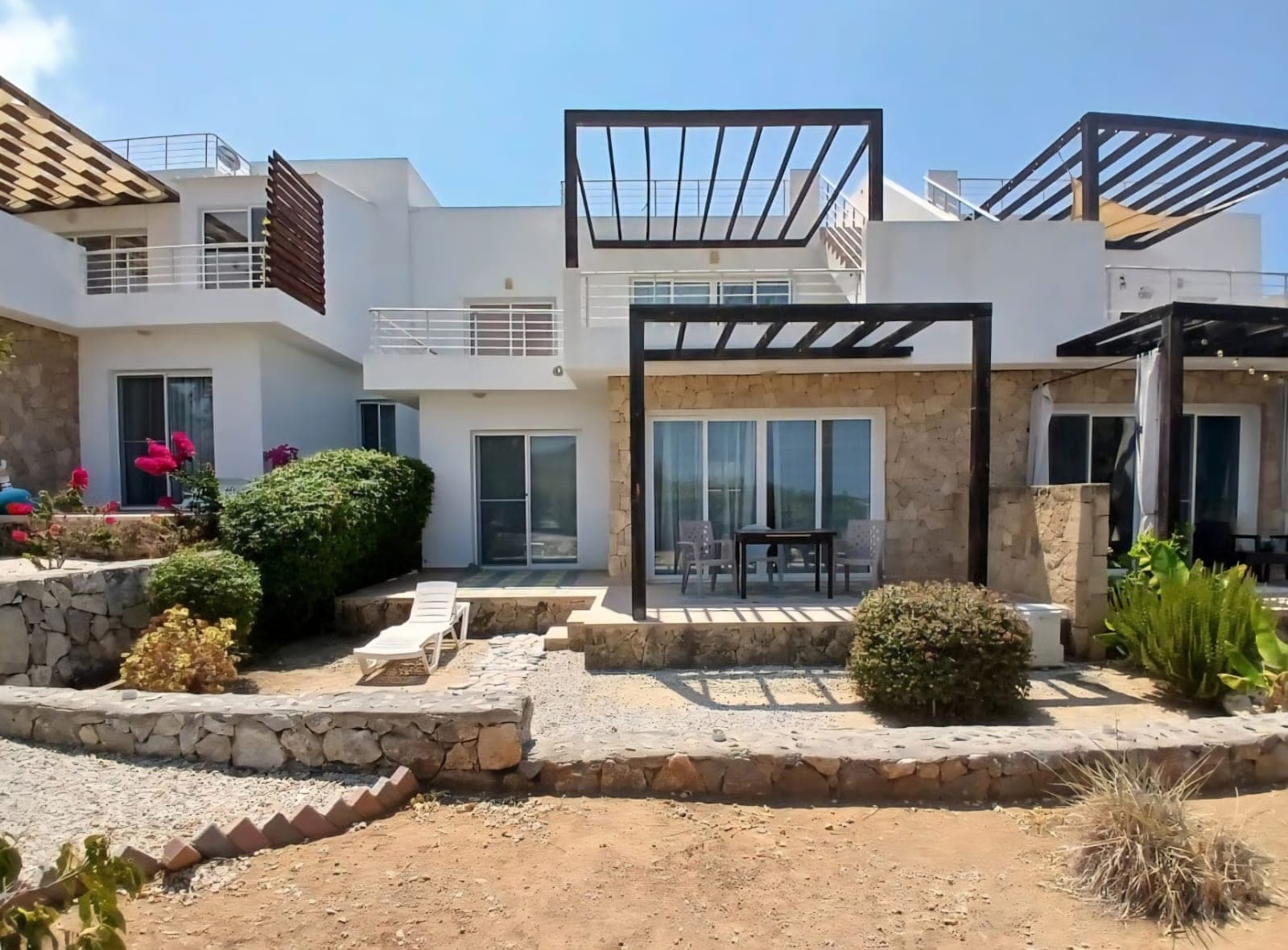 Modern residences with white facades, stone details, and pergolas.