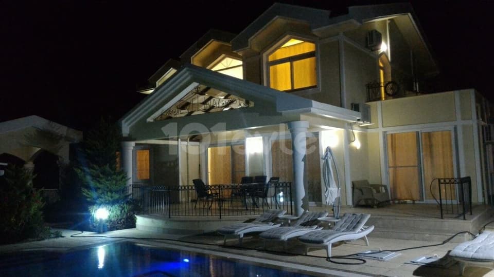 Gece aydınlatmalı havuz ve villa dış cephesi, oturma alanı
