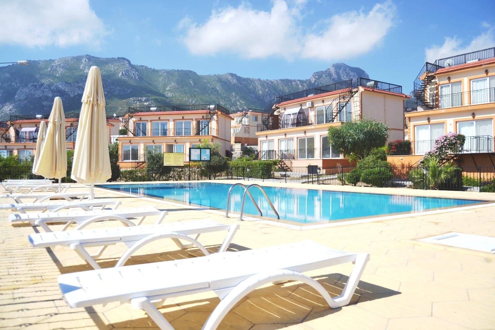 Shared swimming pool with mountain view and surrounding buildings.