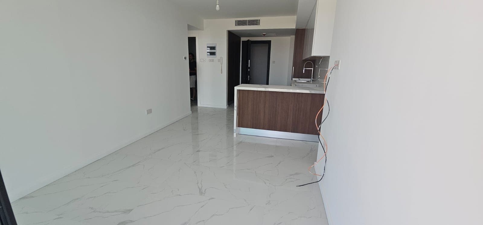Open plan living room and kitchen area, white tiled floor.