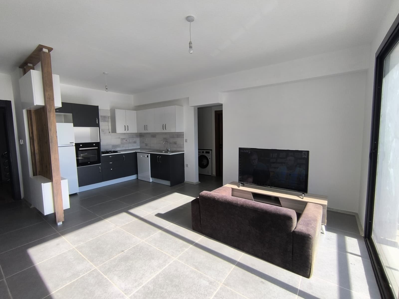 Open-plan living room and kitchen with television and sofa.