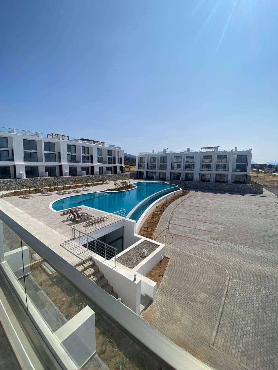 Modern binalar, ortak havuz ve açık otopark alanı.