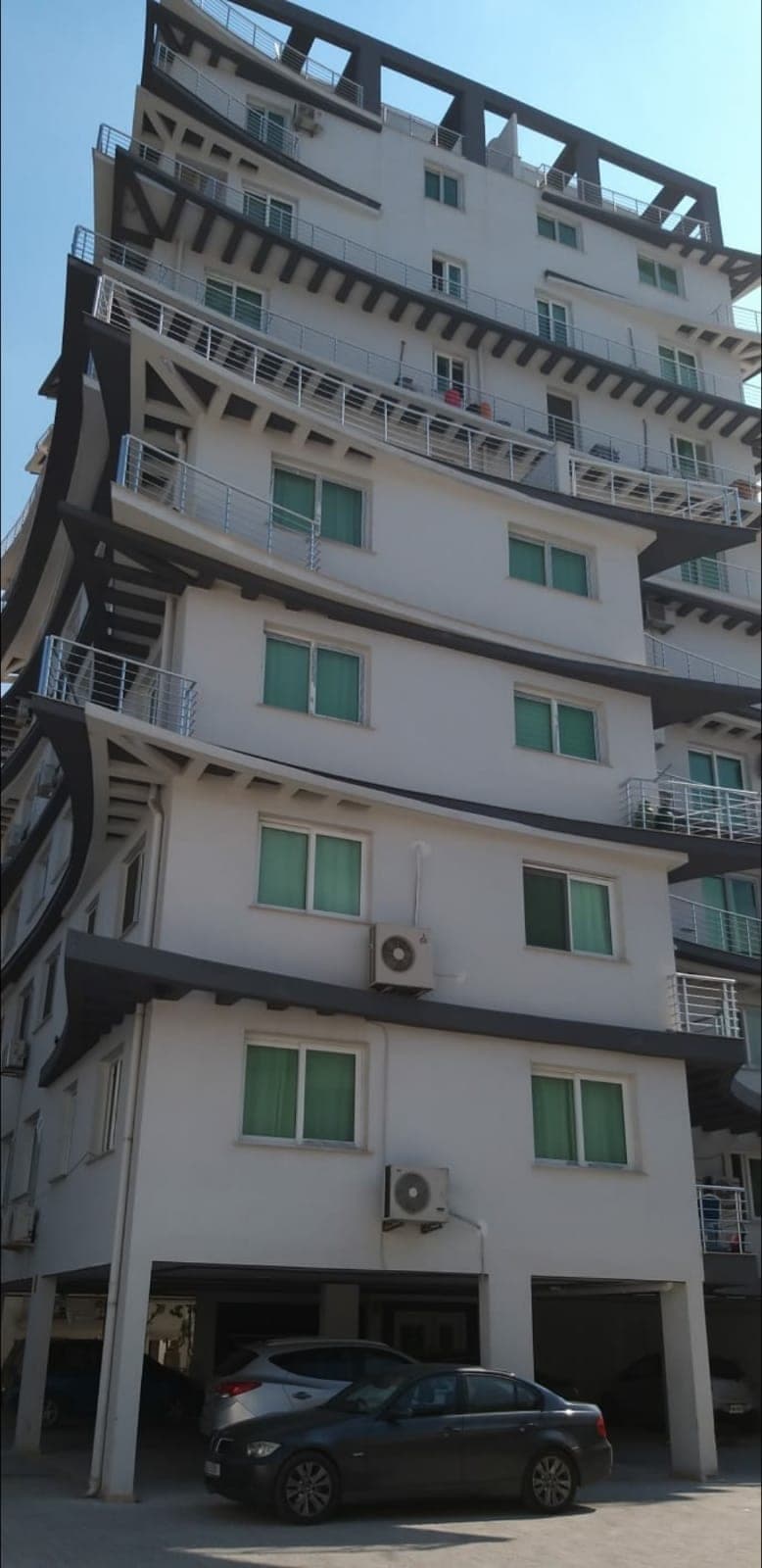 Exterior of a multi-story building with modern architecture and parking area.
