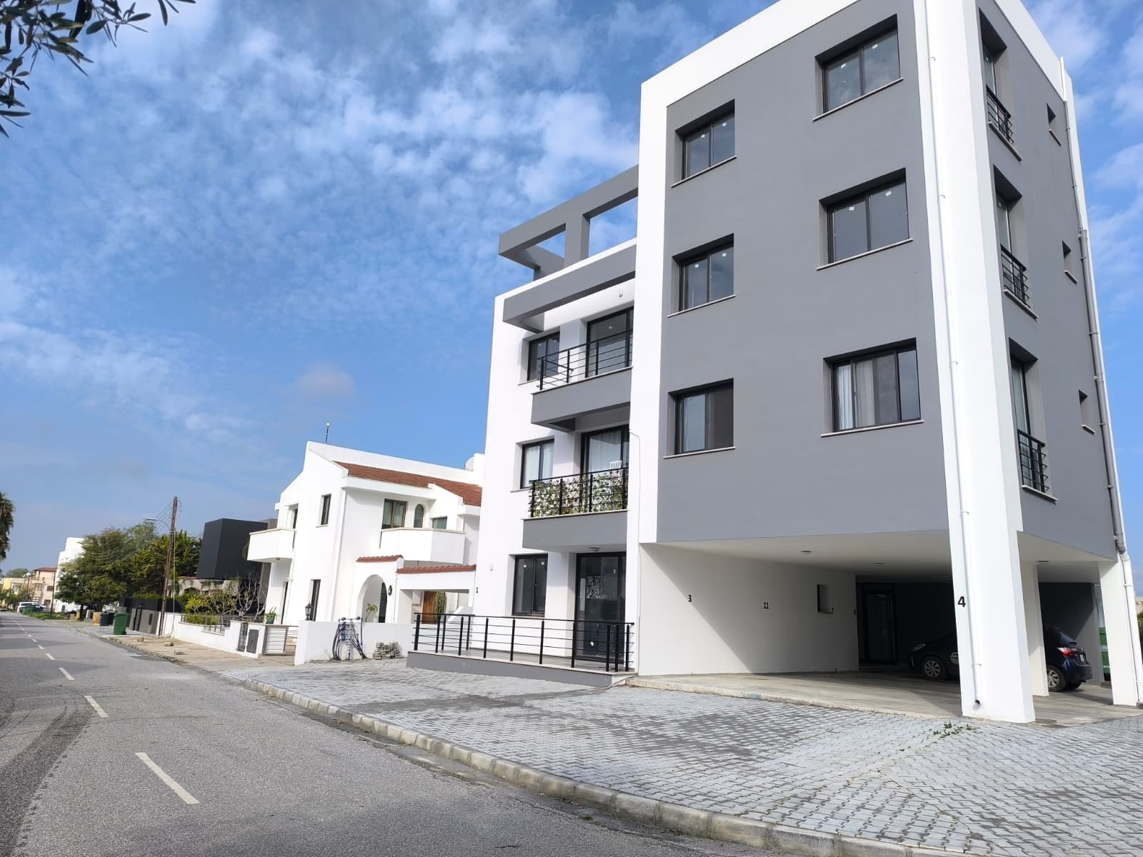 Exterior of a modern apartment building with open parking area.