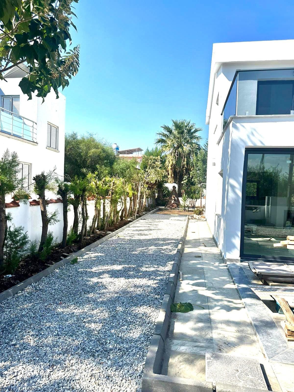 Side facade of the white villa with a long gravel garden path