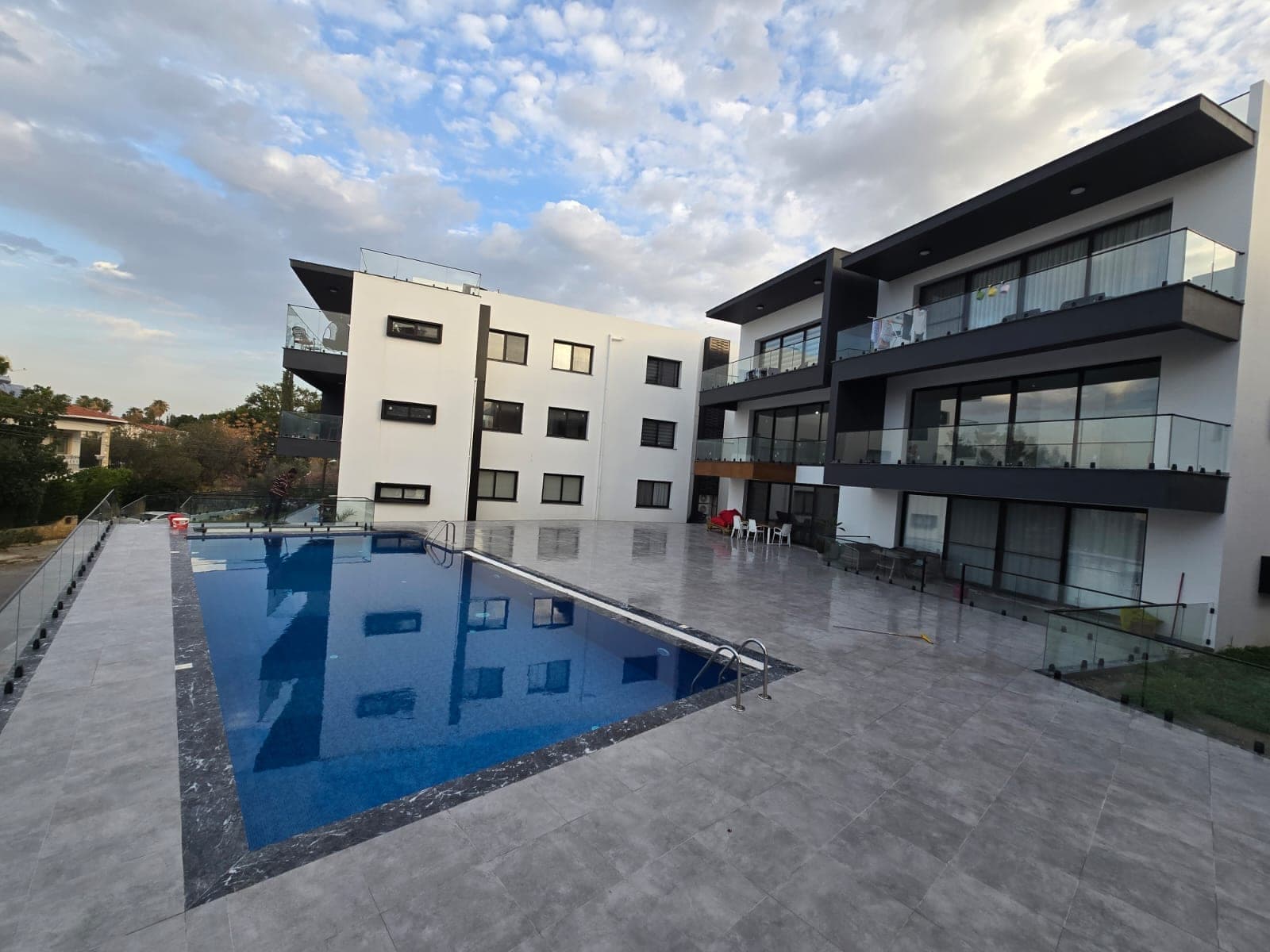 Modern apartment building with a shared swimming pool in front.