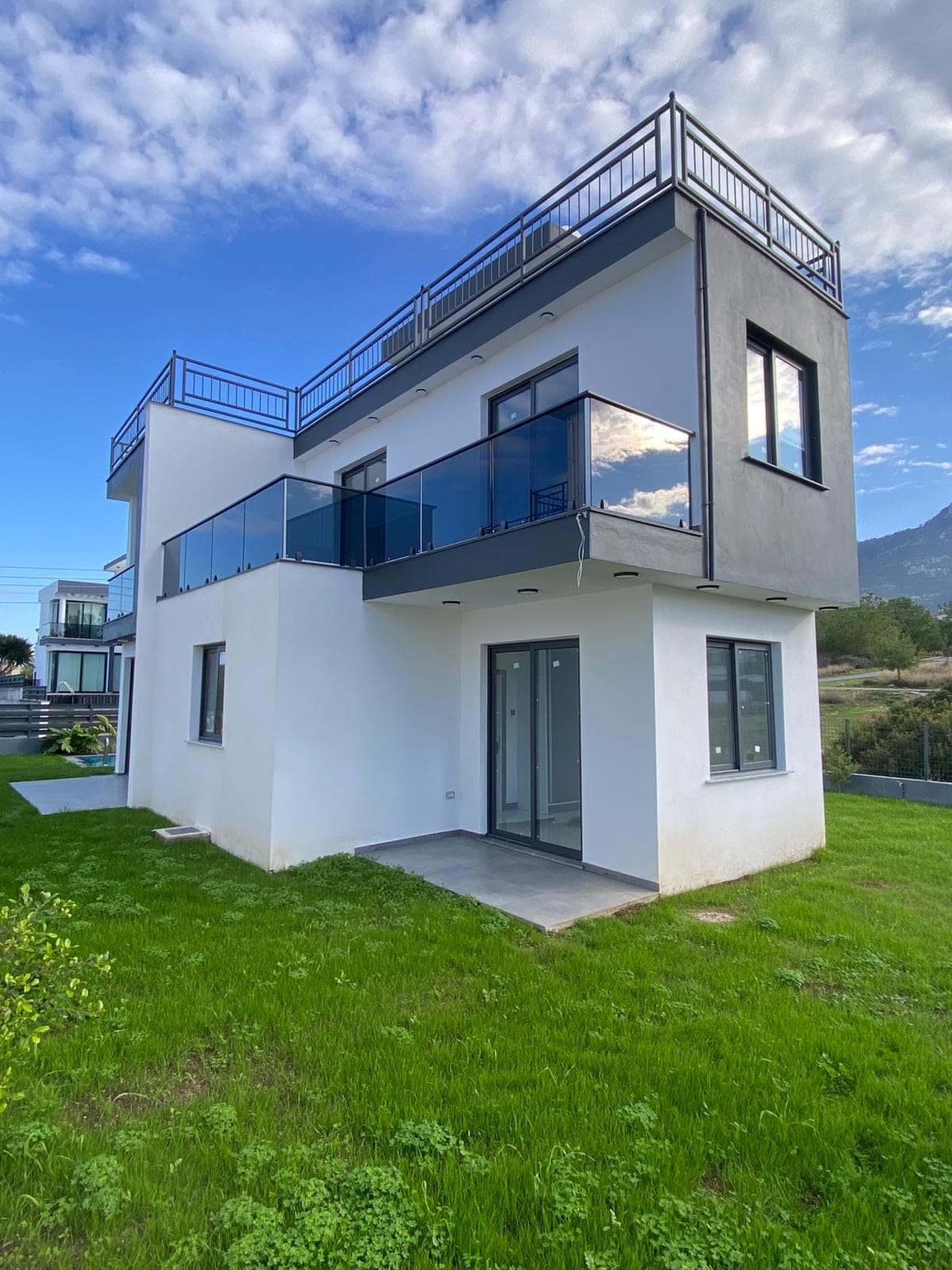 Modern architecture villa exterior in white and grey tones, with a spacious garden.