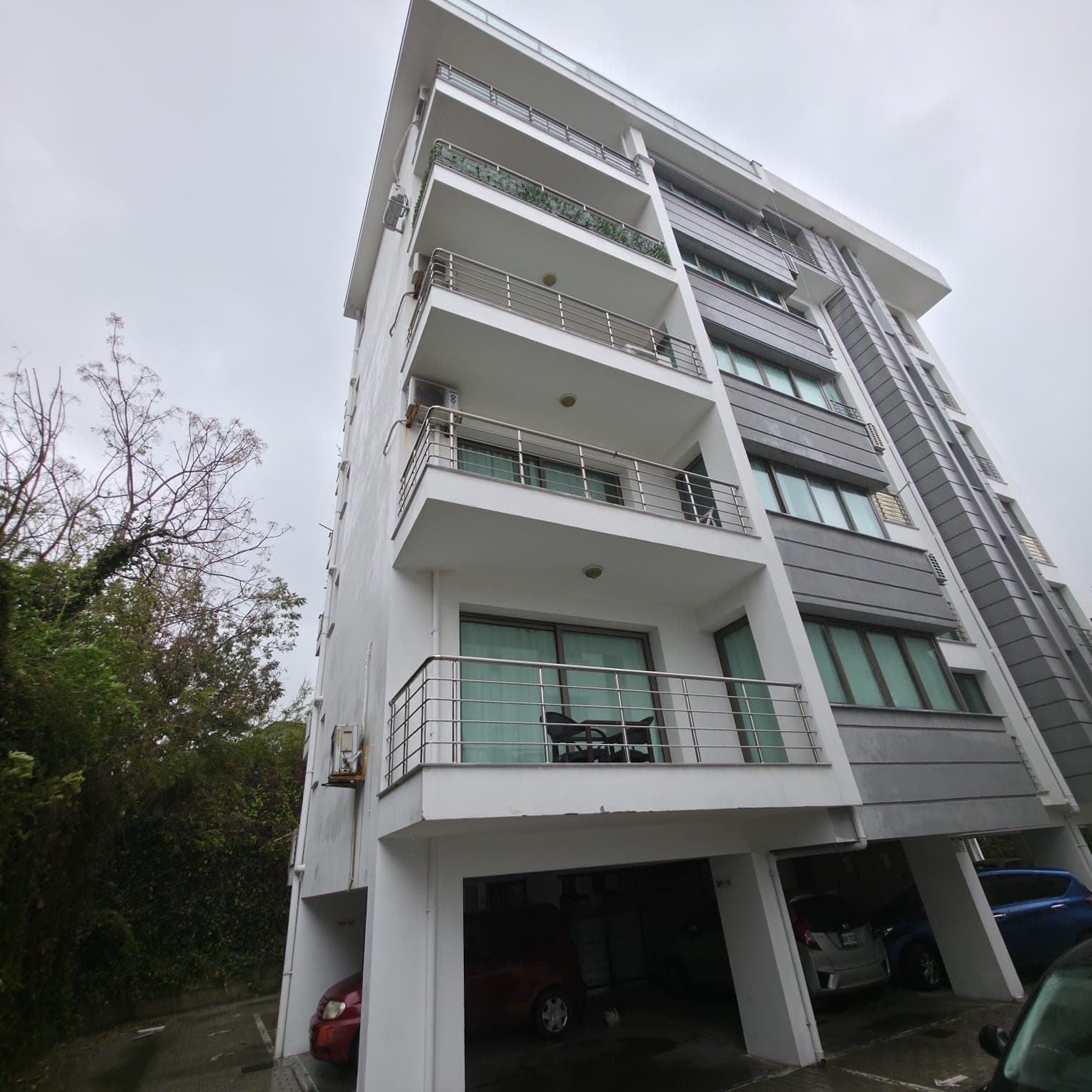 Exterior of a modern apartment building with ground floor parking.