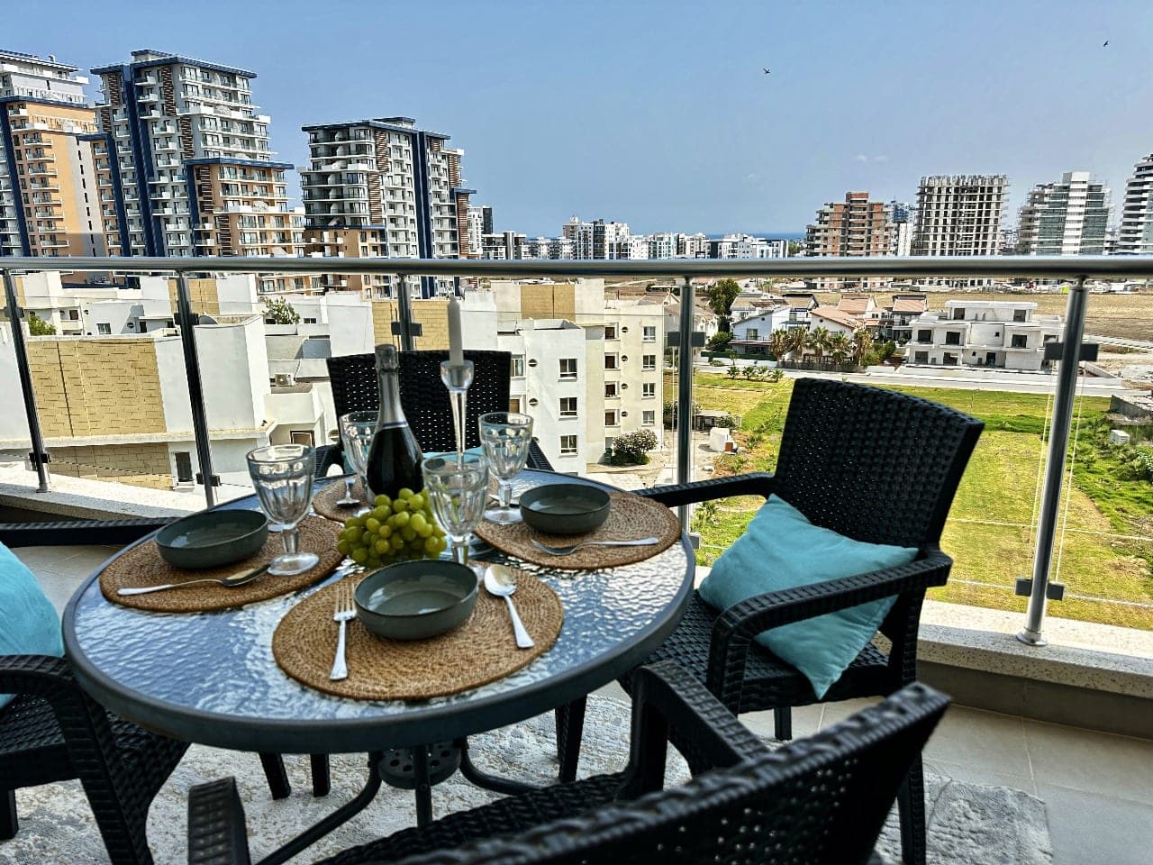 Dining table and chairs on balcony with city and sea view