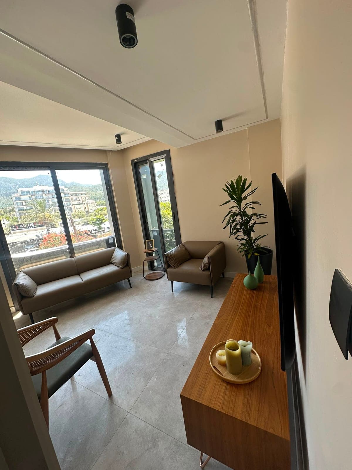 Living room with large windows, brown sofas and city/sea view.