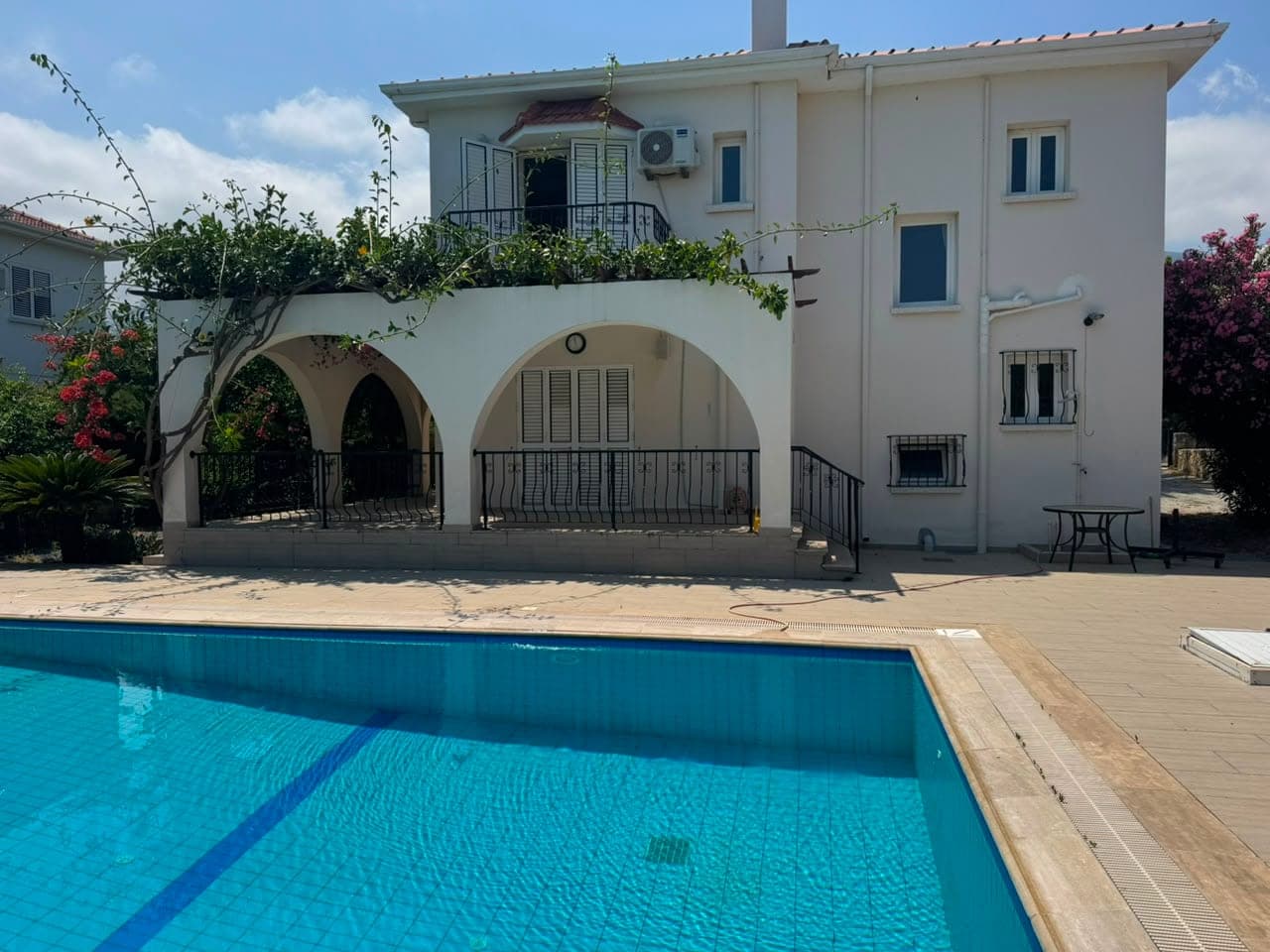 White-fronted villa with a pool and arched veranda