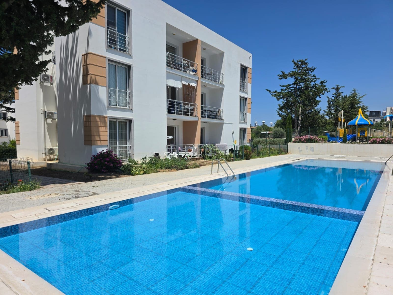 Shared swimming pool and playground in front of the apartment building.