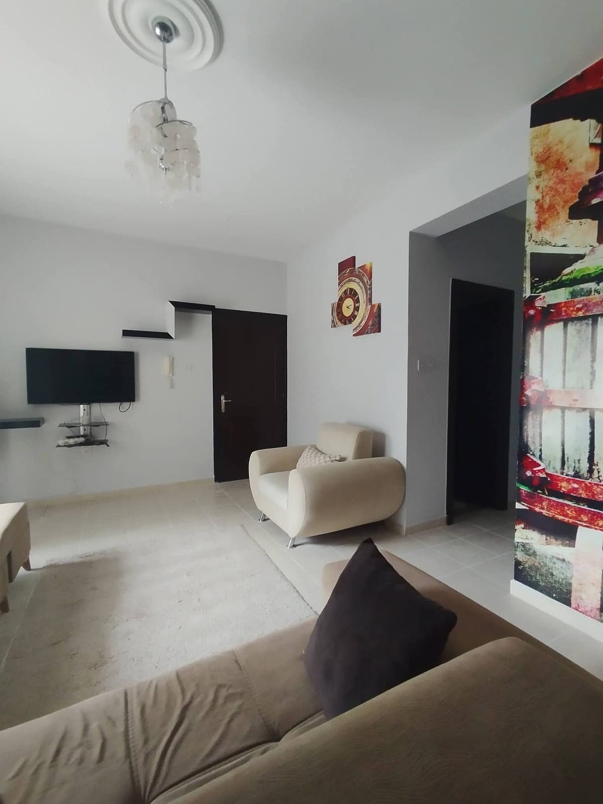 Televizyon ve tekli koltuk içeren, açık renkli modern salon.