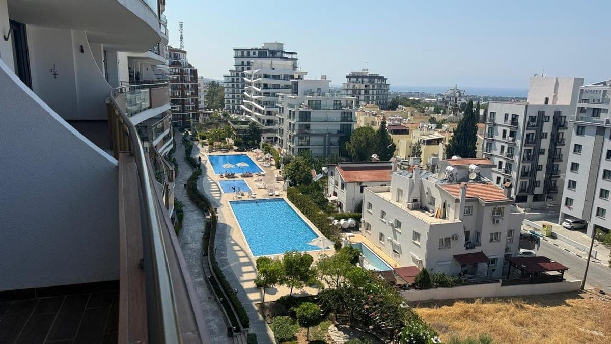 Balcony view of city, multiple pools, and distant sea