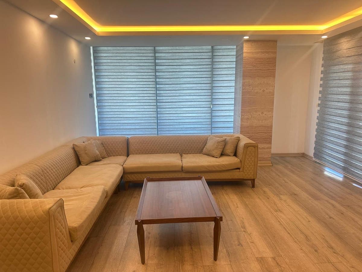 Modern living room with a large L-shaped sofa and wooden floor.