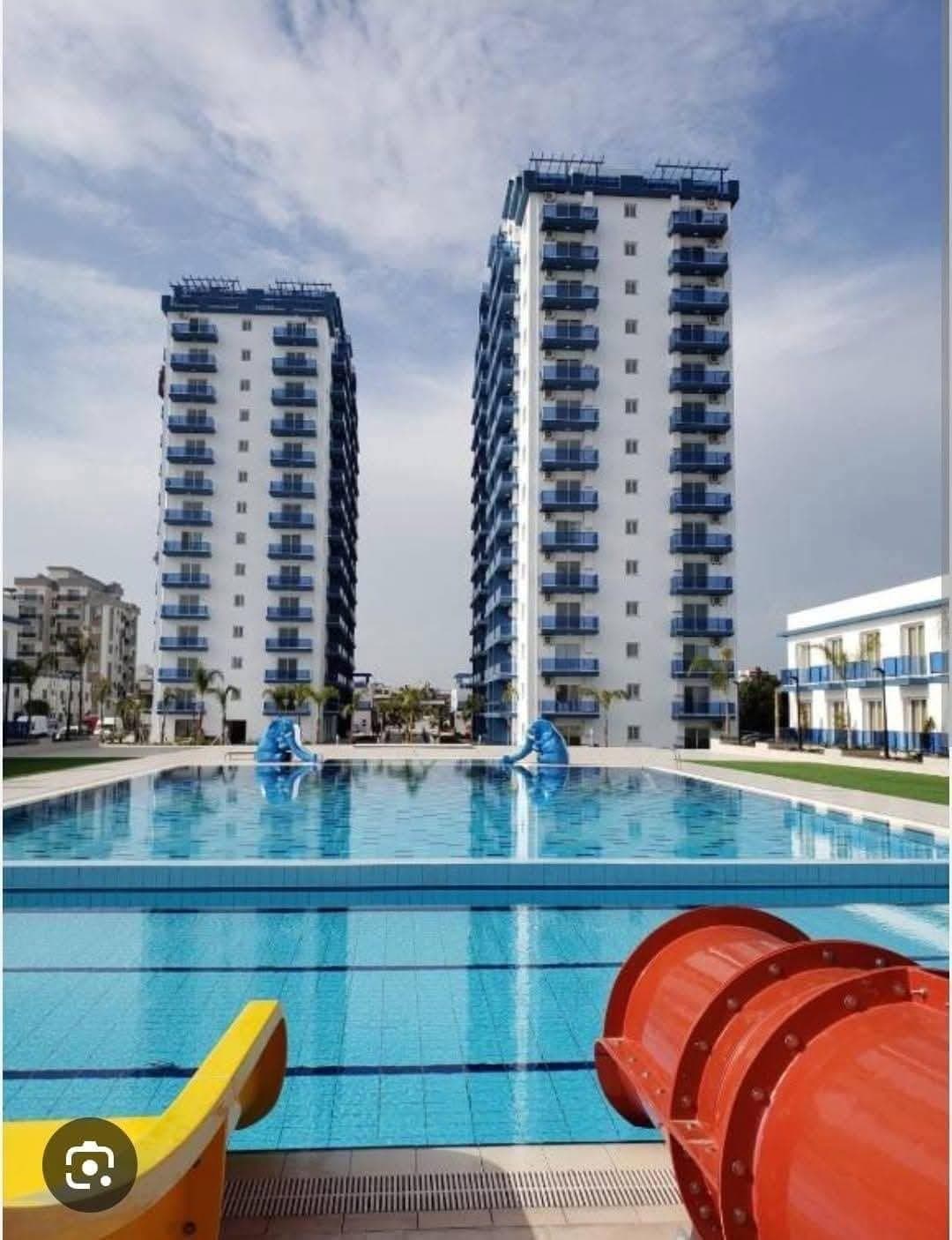 Two high-rise apartment buildings and a large pool with a water slide.
