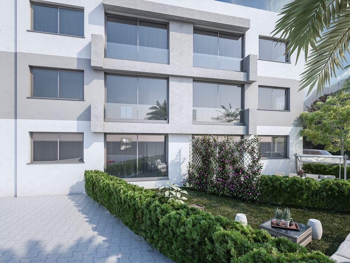 Front facade of a modern building with landscaped garden and glass balconies.