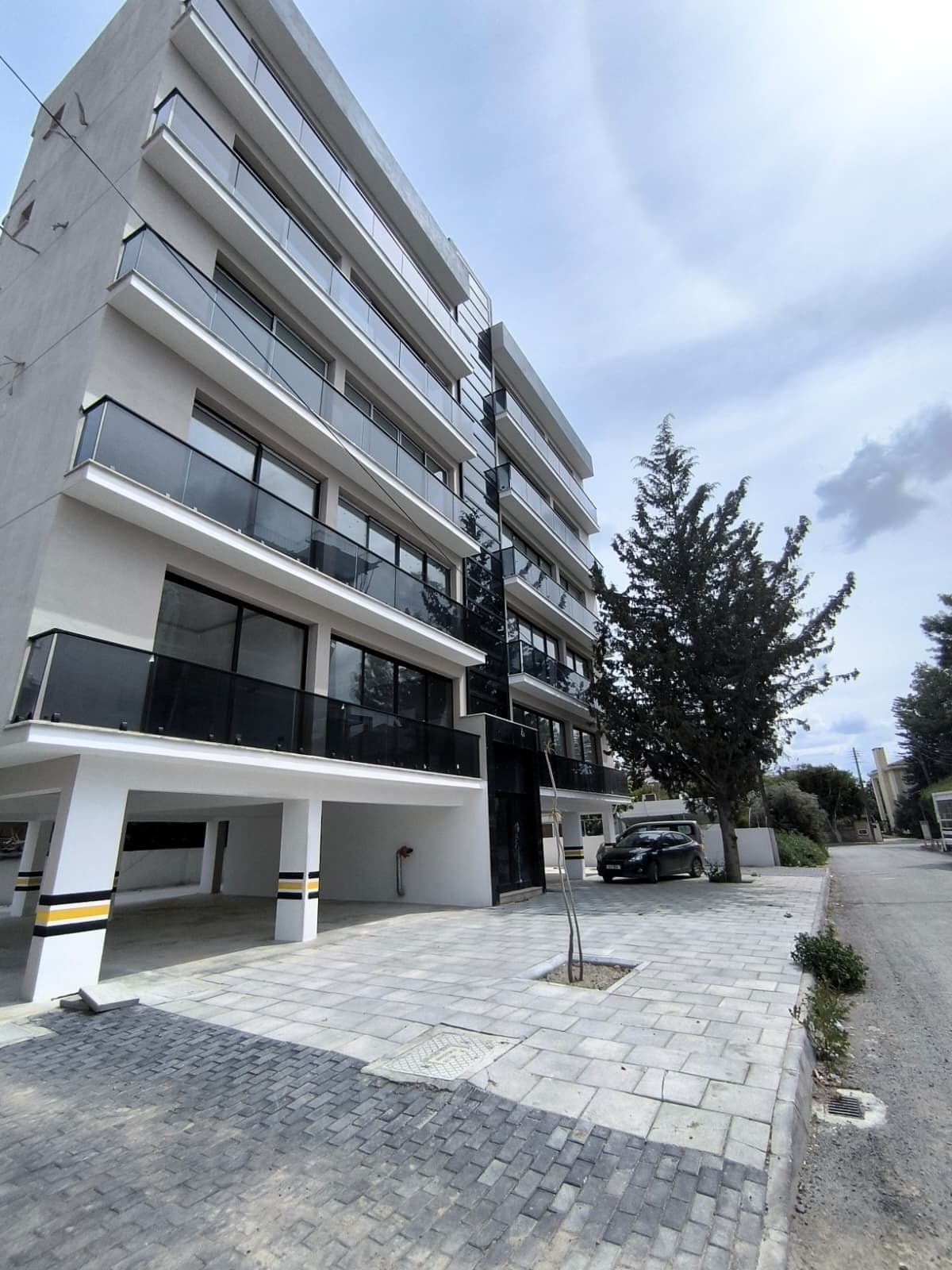 Exterior of a modern multi-story building with covered parking area.