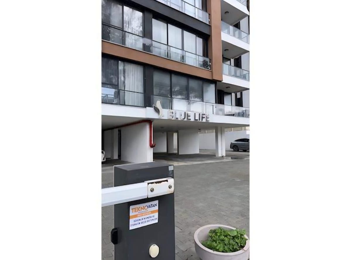 Entrance of a modern apartment building and barrier-controlled parking area.