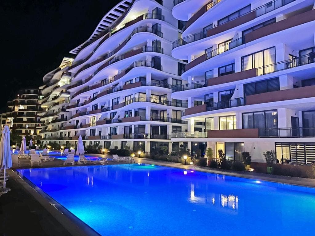 Modern apartment building and illuminated swimming pool, night view.