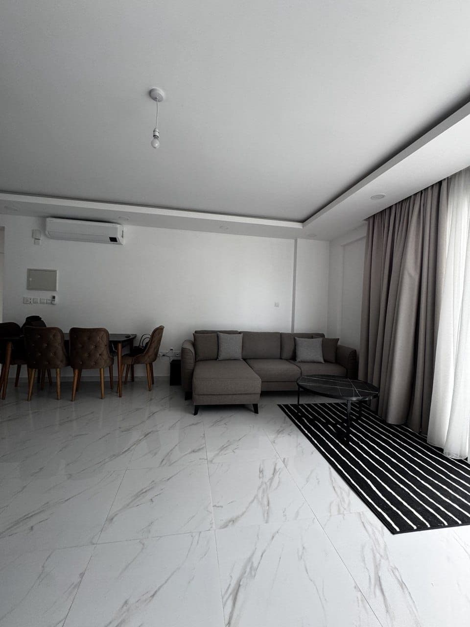 Spacious living room and dining area with modern furniture and air conditioning.