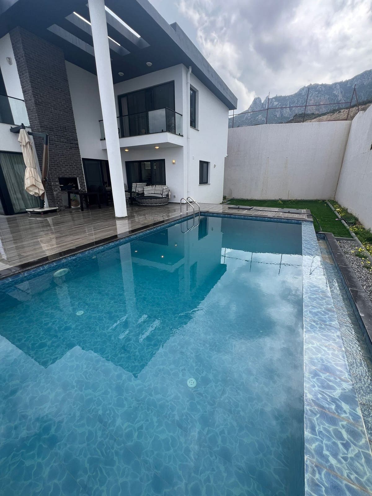 Exterior of a modern detached house with pool and mountain view.