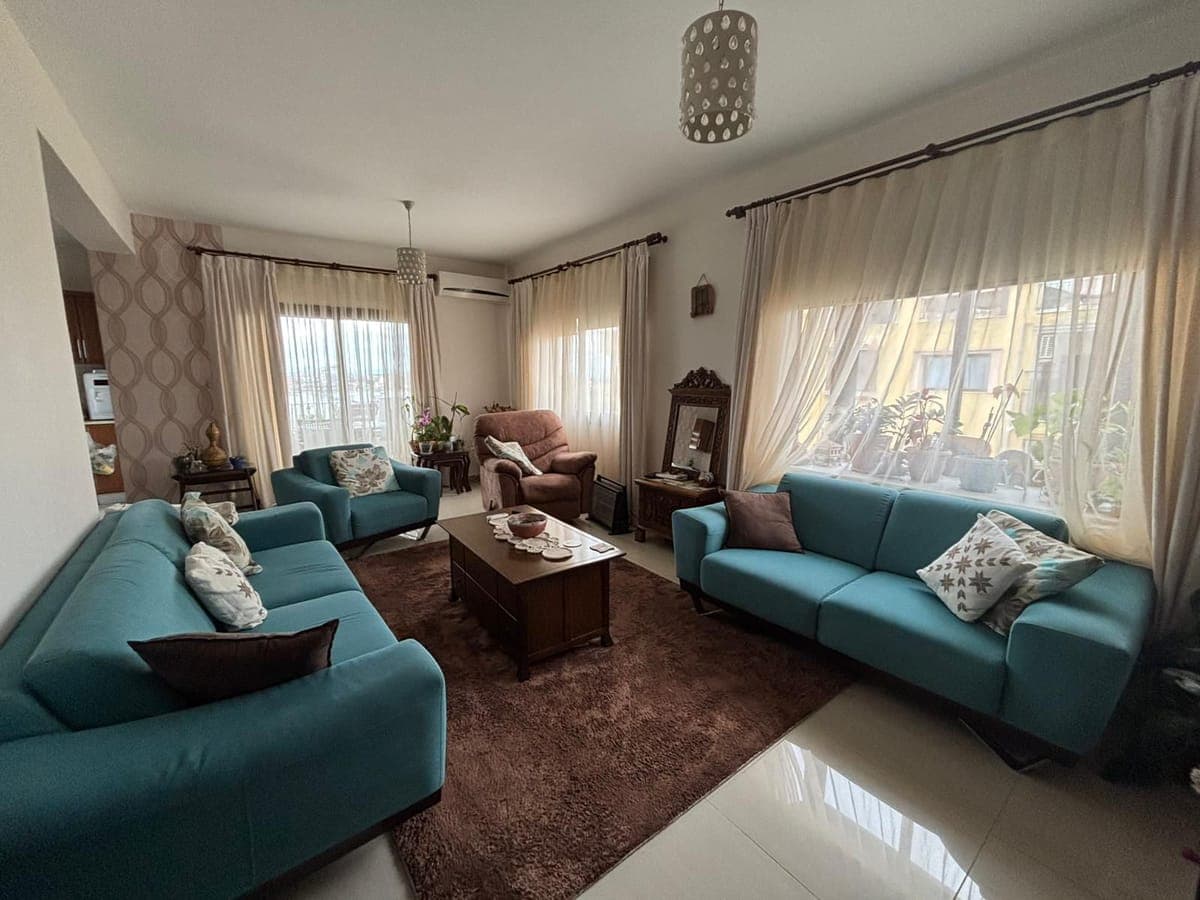 Bright living room with turquoise sofas and large windows.