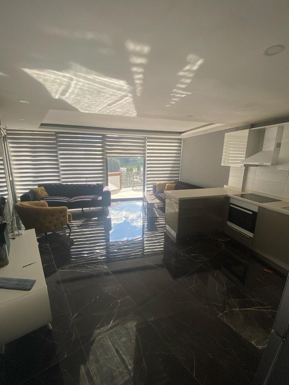 Open-plan living room, kitchen island, and windows opening to a balcony.