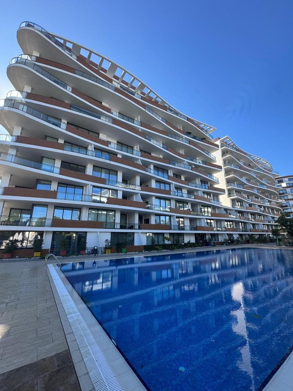 Modern designed apartment building with a swimming pool in front.
