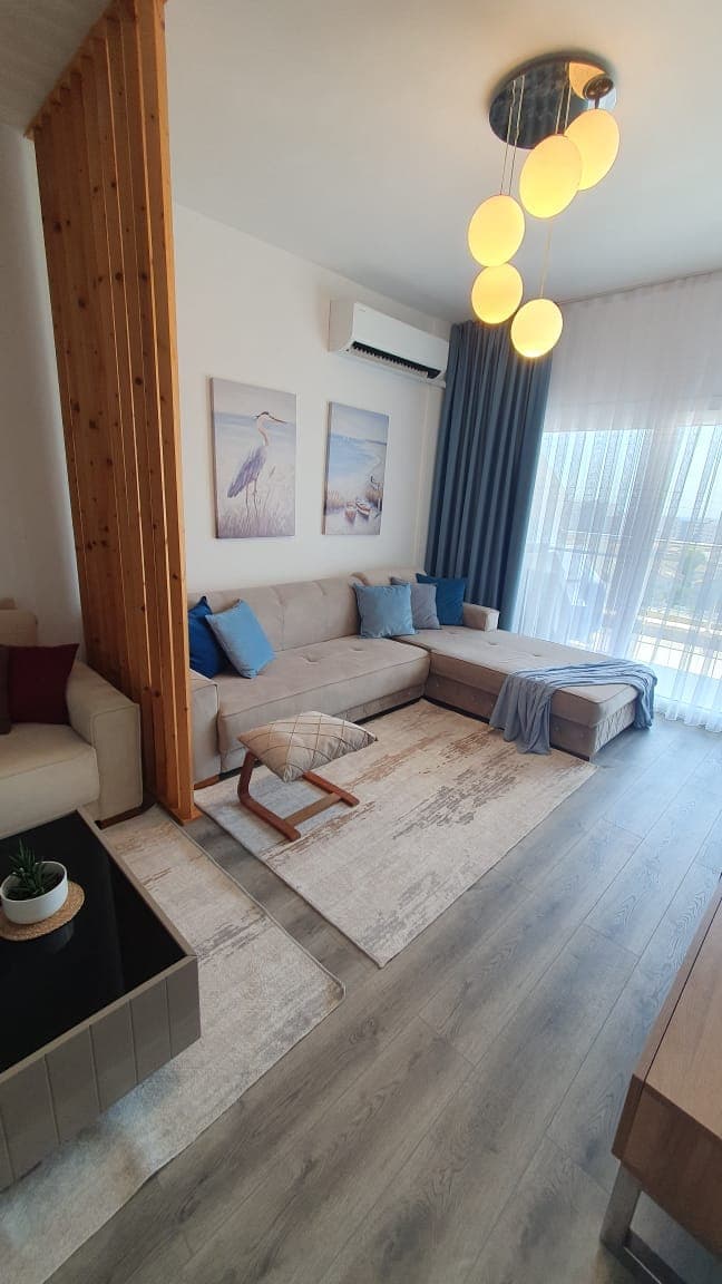 L koltuklu modern salon, ahşap bölücü ve balkona açılan pencere.