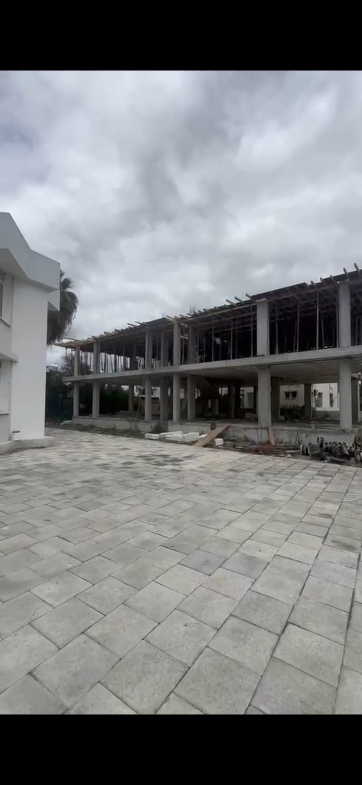 Exterior of the building under construction with a large paved area.