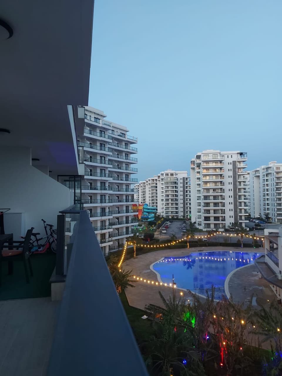 Balkondan havuz, site ve diğer binaların akşam manzarası.