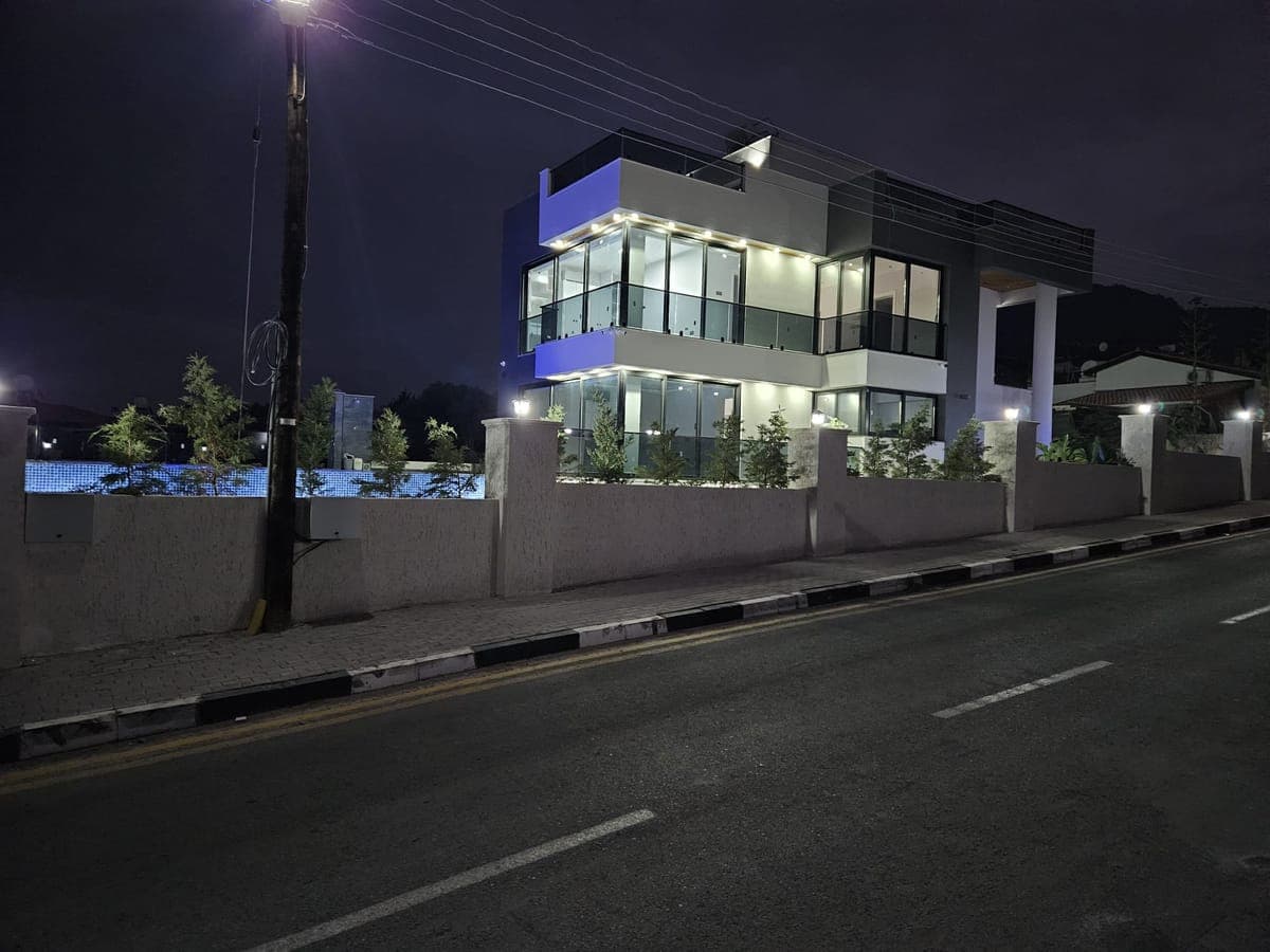 Gece aydınlatmalı modern müstakil evin dış cephesi ve havuz.