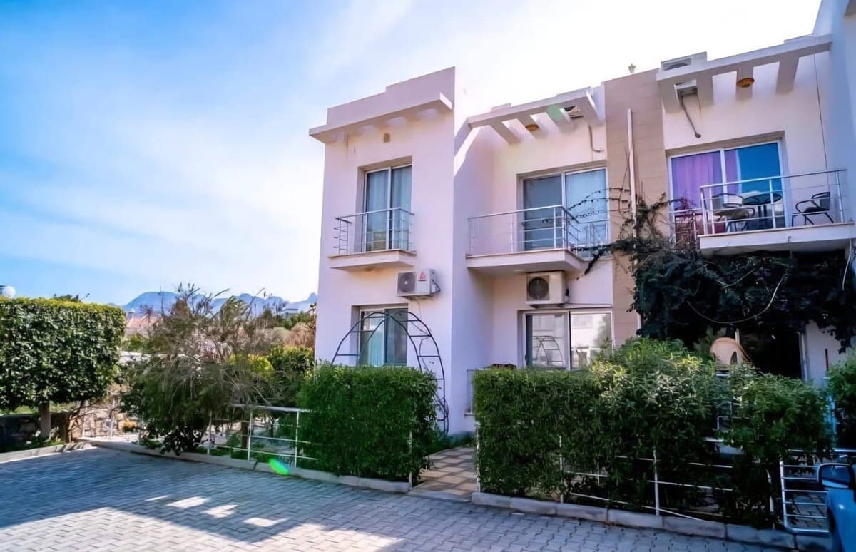 Exterior of a detached house with garden, balconies, and parking area.